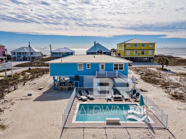 rear view of property featuring a water view, a fenced in pool, and a patio