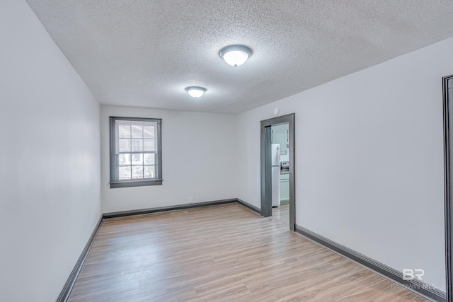 spare room featuring a textured ceiling and light hardwood / wood-style flooring