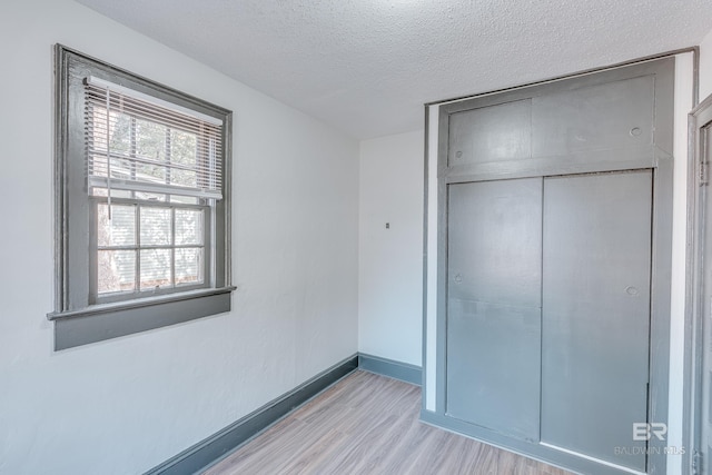 unfurnished bedroom featuring a textured ceiling, a closet, and light wood-type flooring