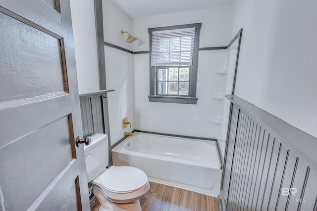 bathroom with toilet, wood-type flooring, and shower / tub combination