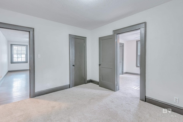 unfurnished bedroom featuring a textured ceiling and light colored carpet