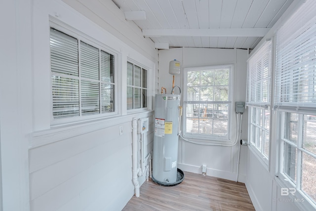 sunroom with electric water heater, lofted ceiling with beams, and wooden ceiling