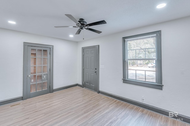 empty room with ceiling fan and light hardwood / wood-style floors