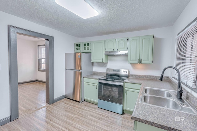 kitchen with sink, green cabinets, light hardwood / wood-style flooring, appliances with stainless steel finishes, and a textured ceiling