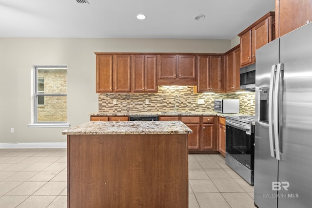 kitchen with light stone countertops, sink, stainless steel appliances, and a center island