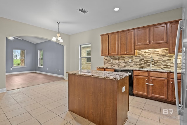 kitchen featuring black dishwasher, tasteful backsplash, sink, light stone counters, and a center island