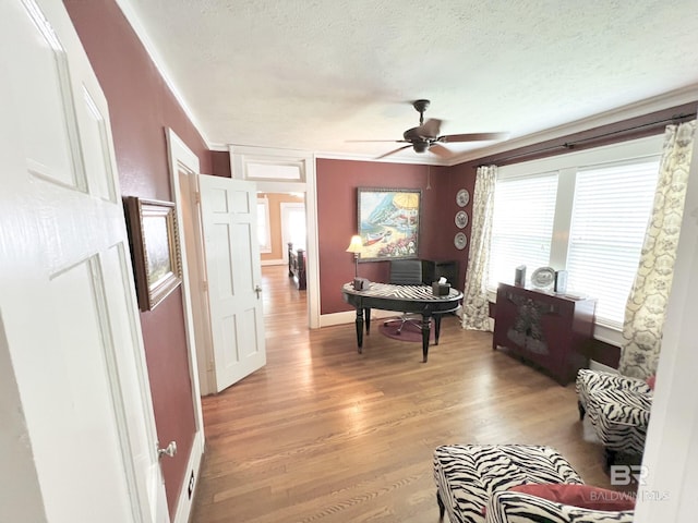 interior space featuring crown molding, a textured ceiling, wood-type flooring, and ceiling fan