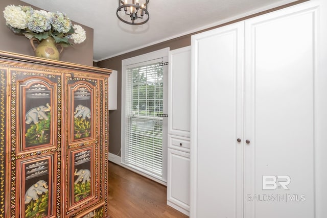 corridor featuring crown molding, hardwood / wood-style floors, and a notable chandelier