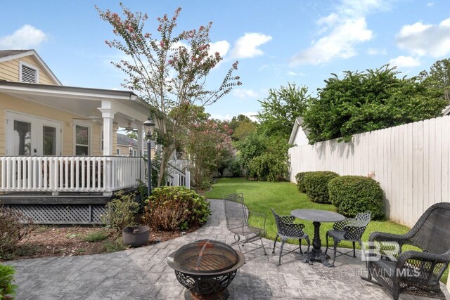 view of yard with a fire pit, french doors, ceiling fan, and a patio area