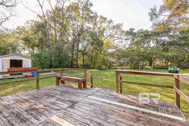 wooden terrace featuring a storage shed, a lawn, and an outdoor structure