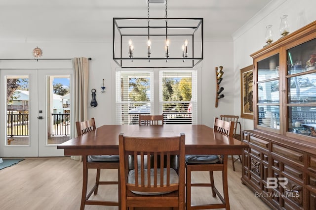 dining area featuring light wood-style flooring, ornamental molding, and french doors