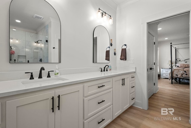 full bathroom featuring double vanity, a sink, a shower stall, and wood finished floors