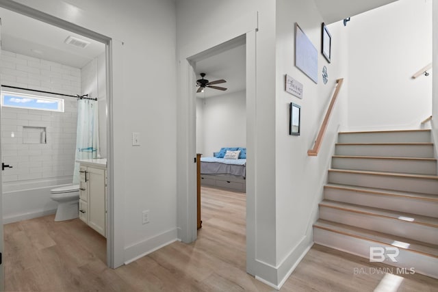 interior space featuring visible vents, ensuite bath, wood finished floors, shower / bath combo with shower curtain, and vanity