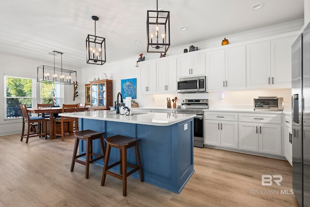 kitchen featuring a center island with sink, white cabinets, stainless steel appliances, light countertops, and a sink