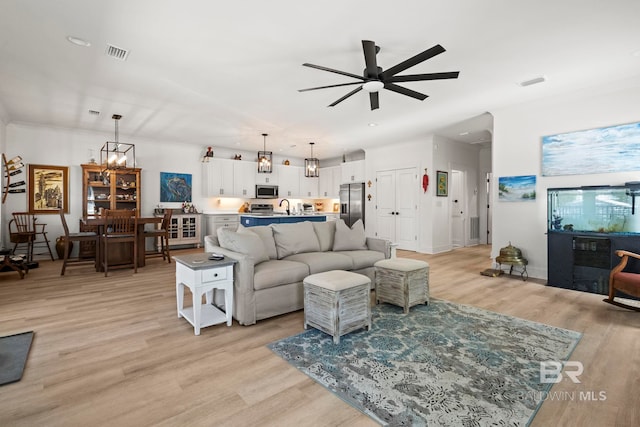 living area with light wood-type flooring, visible vents, recessed lighting, and ceiling fan with notable chandelier