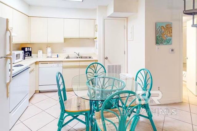 kitchen with white appliances, white cabinetry, sink, and light tile patterned floors