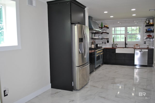 kitchen with decorative backsplash, stainless steel appliances, sink, and wall chimney range hood