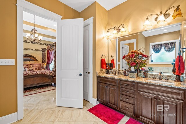 bathroom with tile flooring, an inviting chandelier, oversized vanity, and dual sinks