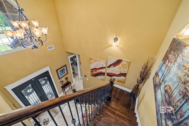 staircase featuring a towering ceiling, an inviting chandelier, and hardwood / wood-style floors