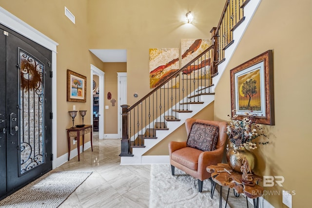 tiled entrance foyer featuring a towering ceiling and french doors