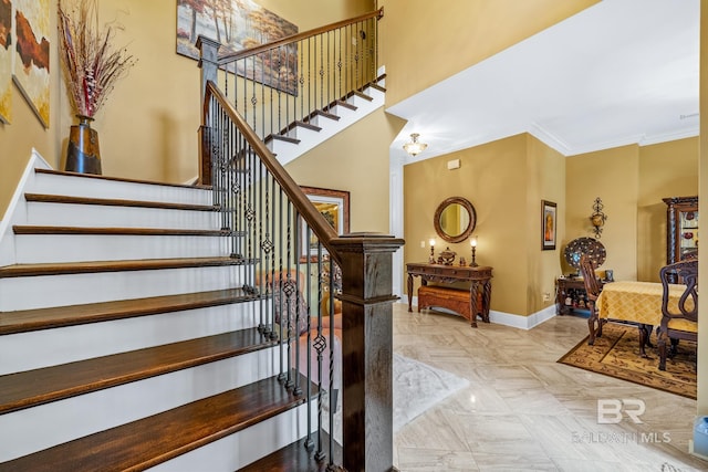 staircase featuring a high ceiling, ornamental molding, and tile floors