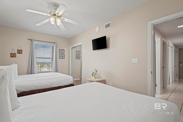 bedroom with a textured ceiling, light tile patterned floors, and ceiling fan