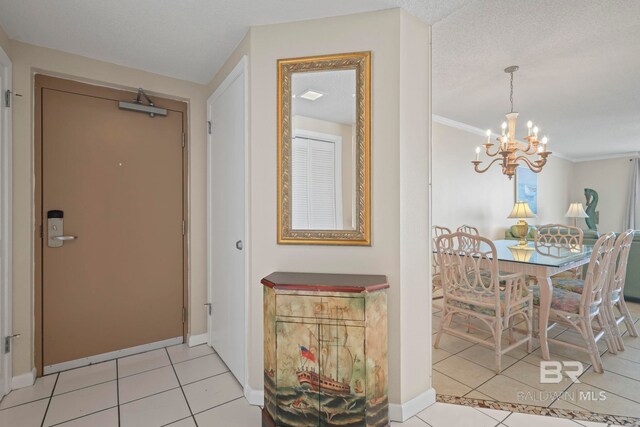 tiled foyer featuring an inviting chandelier, crown molding, and a textured ceiling