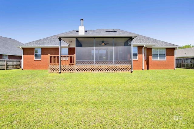 back of house featuring brick siding, a sunroom, fence, and a lawn