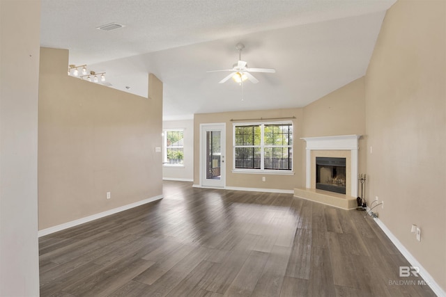 unfurnished living room with a ceiling fan, a fireplace with raised hearth, wood finished floors, and vaulted ceiling