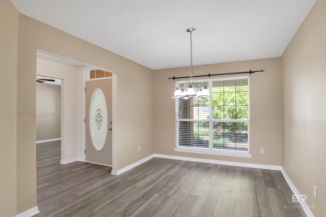 foyer entrance featuring a chandelier, a textured ceiling, wood finished floors, and baseboards