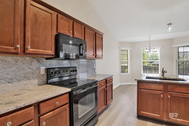 kitchen featuring light stone countertops, a sink, black appliances, and a wealth of natural light