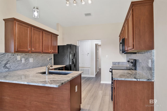 kitchen featuring a peninsula, black appliances, light stone countertops, visible vents, and a sink