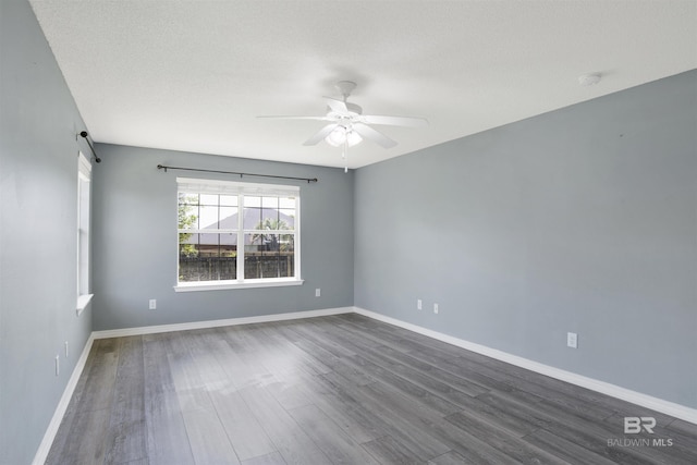 unfurnished room featuring dark wood-type flooring, a textured ceiling, baseboards, and a ceiling fan