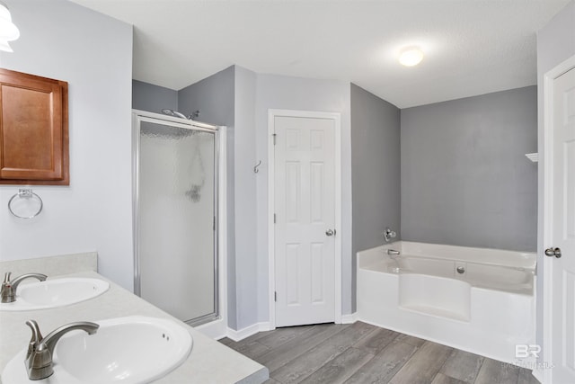 bathroom featuring a sink, a stall shower, wood finished floors, and a garden tub
