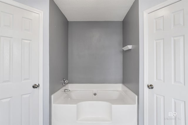 bathroom with a bath and a textured ceiling