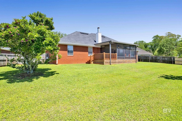 back of property featuring a sunroom, a fenced backyard, brick siding, and a lawn