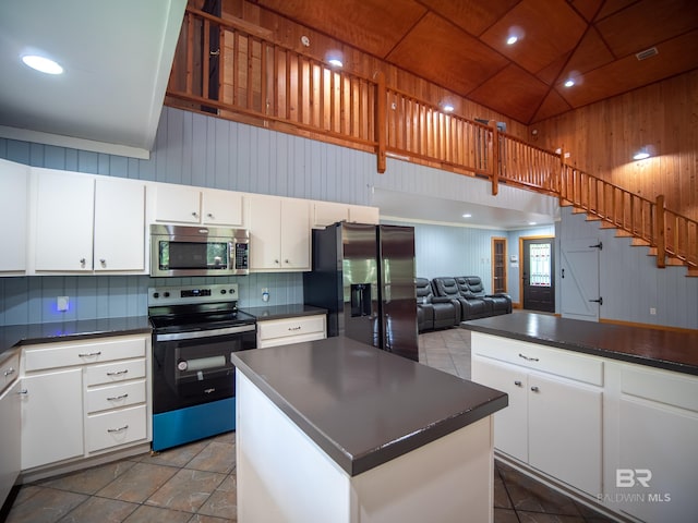 kitchen with black fridge with ice dispenser, stainless steel microwave, electric range, dark countertops, and white cabinets