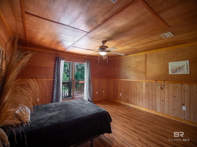 bedroom with visible vents, wooden walls, wood finished floors, a ceiling fan, and wood ceiling