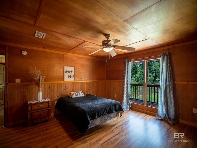 bedroom with visible vents, access to outside, wooden walls, and wood finished floors