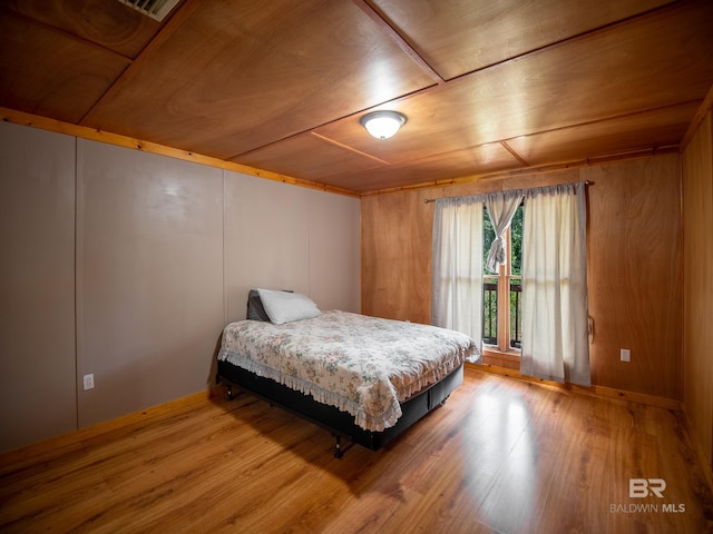 bedroom with wood ceiling, wooden walls, and wood finished floors
