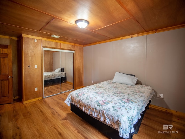 bedroom featuring a closet, wood finished floors, wooden walls, and wood ceiling