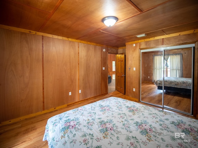 unfurnished bedroom with a closet, wood finished floors, wooden ceiling, and wood walls