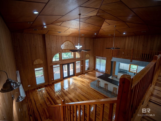 living area featuring hardwood / wood-style flooring, wood walls, a towering ceiling, and recessed lighting