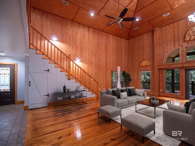living room featuring ceiling fan, stairway, a high ceiling, wooden ceiling, and wood-type flooring