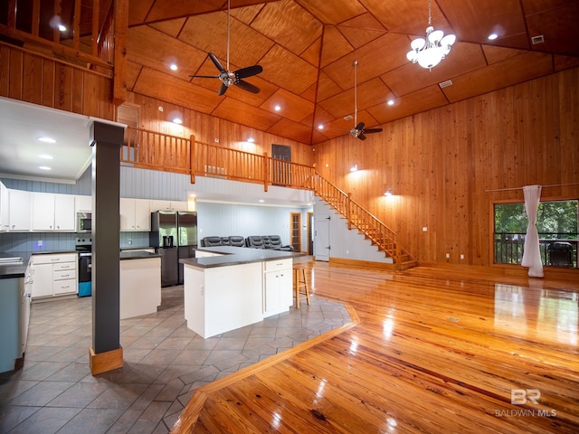 kitchen with open floor plan, high vaulted ceiling, dark countertops, a ceiling fan, and appliances with stainless steel finishes