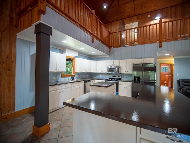 kitchen featuring a sink, dark countertops, appliances with stainless steel finishes, and a towering ceiling