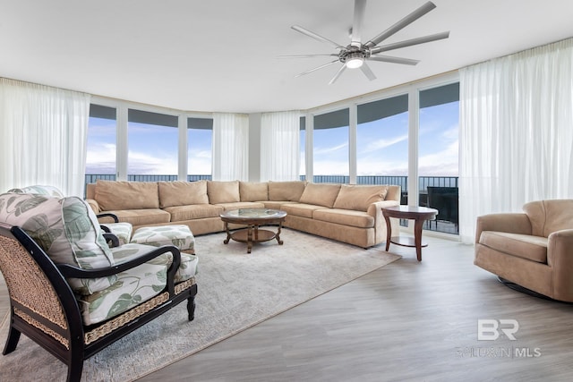 living room featuring a water view, ceiling fan, floor to ceiling windows, and light hardwood / wood-style floors