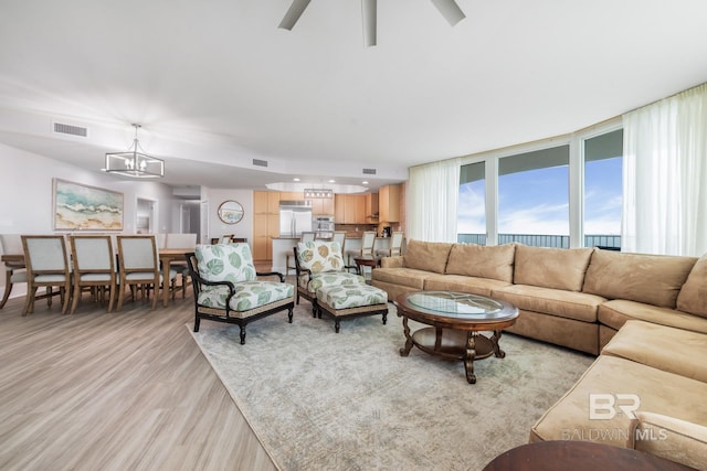 living room with an inviting chandelier, expansive windows, and light hardwood / wood-style flooring