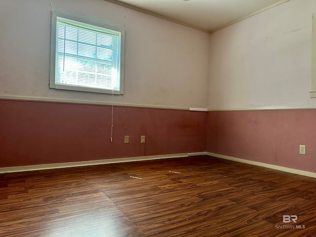 spare room featuring ornamental molding and dark hardwood / wood-style floors