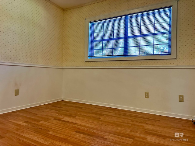 empty room with ornamental molding, light wood-type flooring, and a healthy amount of sunlight